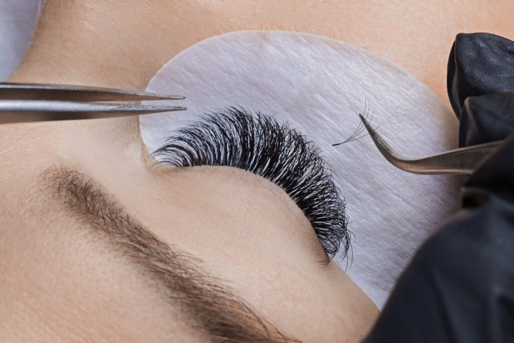 Eyelash extension procedure. Woman master making long lash